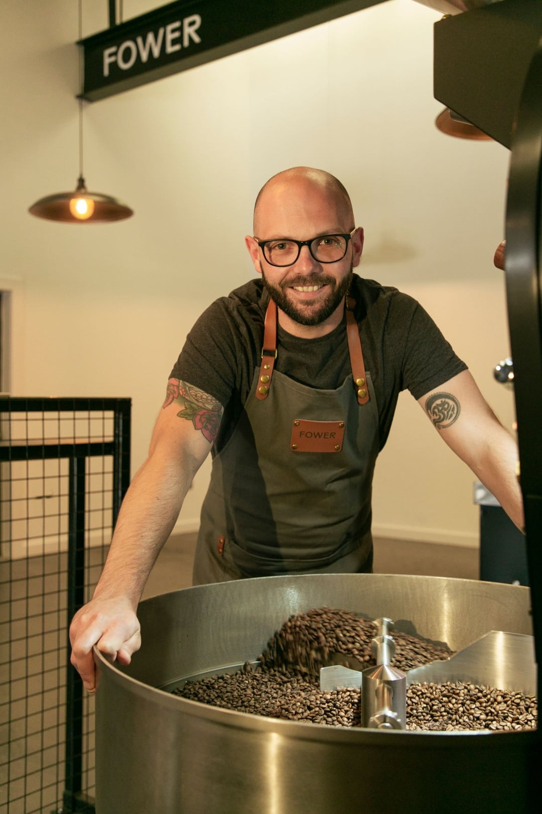 Stuart Jamieson, founder of Fower Coffee, stands over a coffee roaster, where freshly roasted coffee beans are cooling